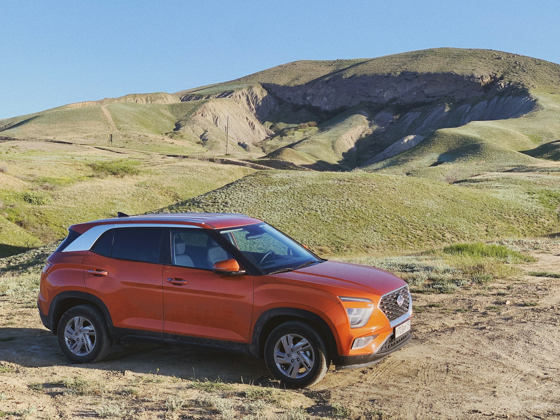 an orange suv parked on a dirt road